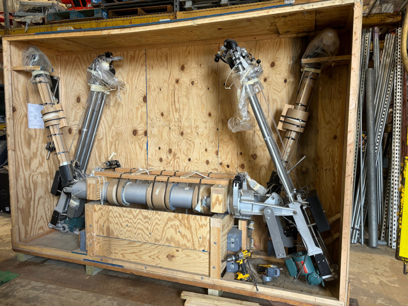 A wooden shipping container opened up to show a metal manipulator machine