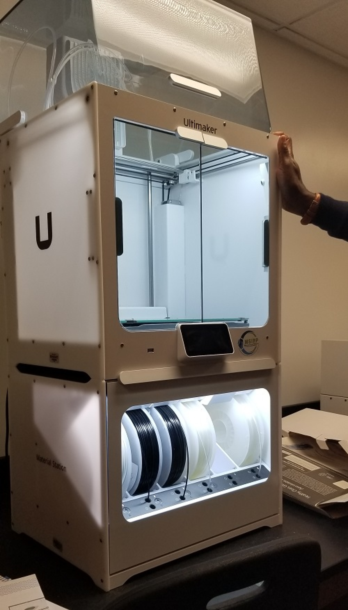 A large, white 3D printer inside a laboratory