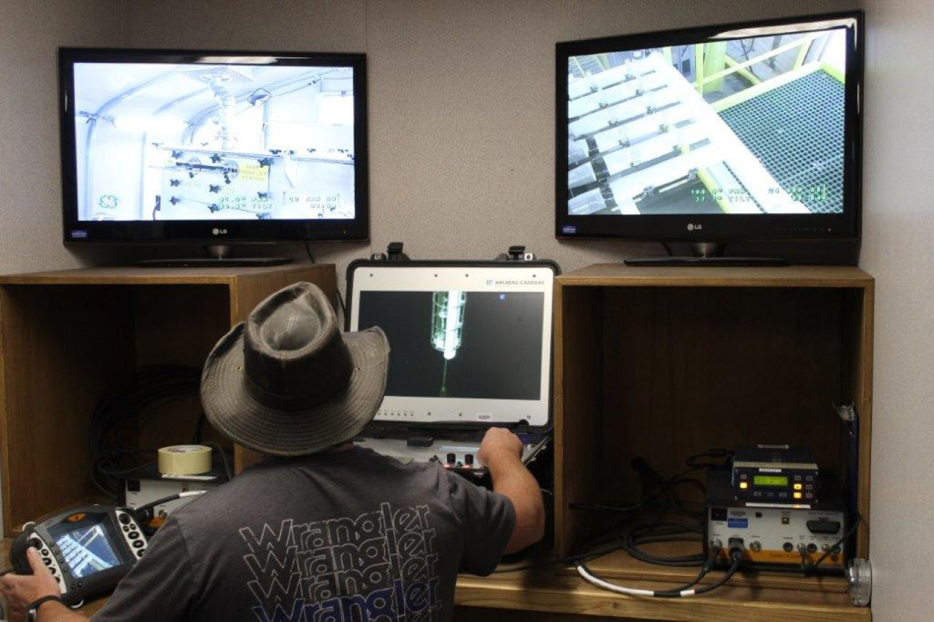 A man sits in front of three different screens and works/monitors on them