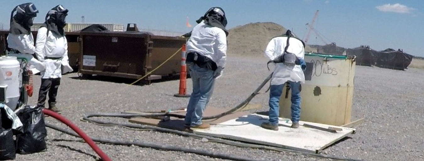 Four workers conducting underground blasting, they hold tubes and work on a white, round, large pipe