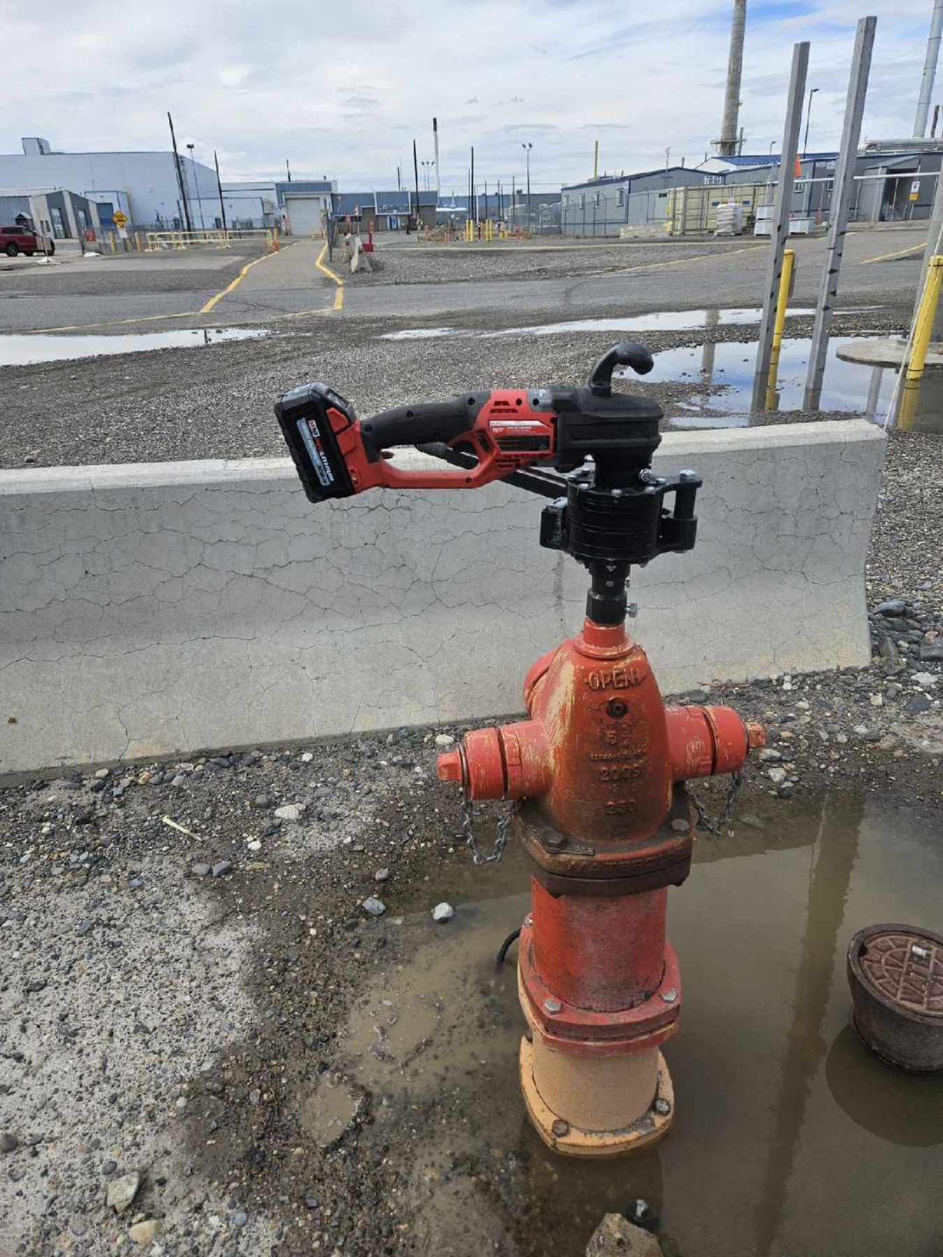 A portable pump on top of a red fire hydrant on a sidewalk