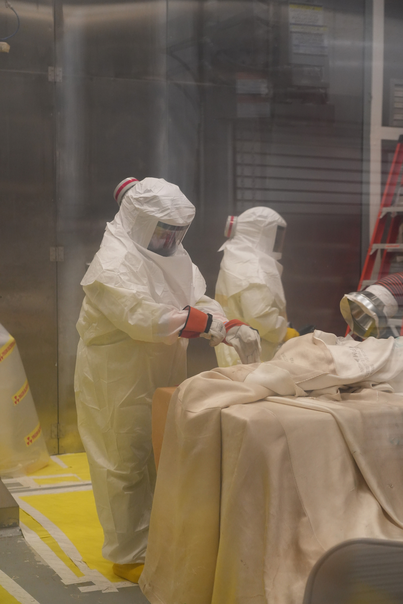 Workers at the Transuranic Waste Processing Center at Oak Ridge place cellulosic waste into premixed grout containers.