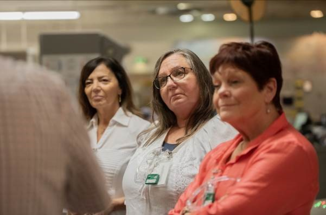Three woman look a person out of the camera frame