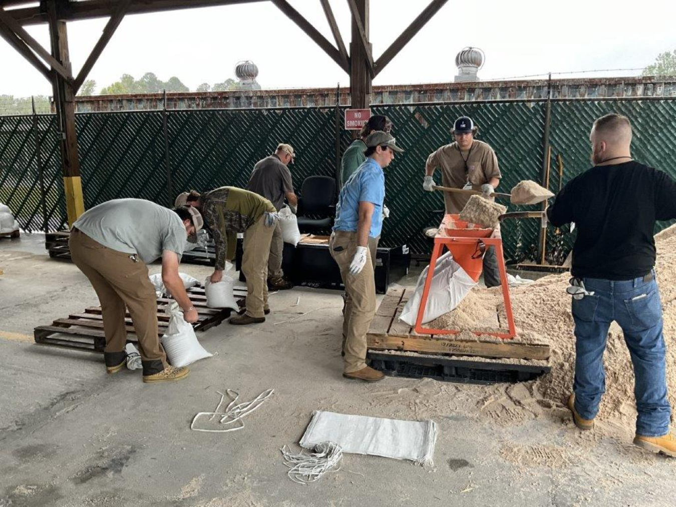 A group of people shoveling sand into sand bags