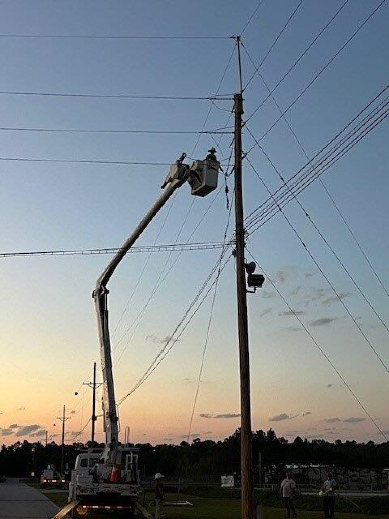 An electric worker in a crane box working on a power line