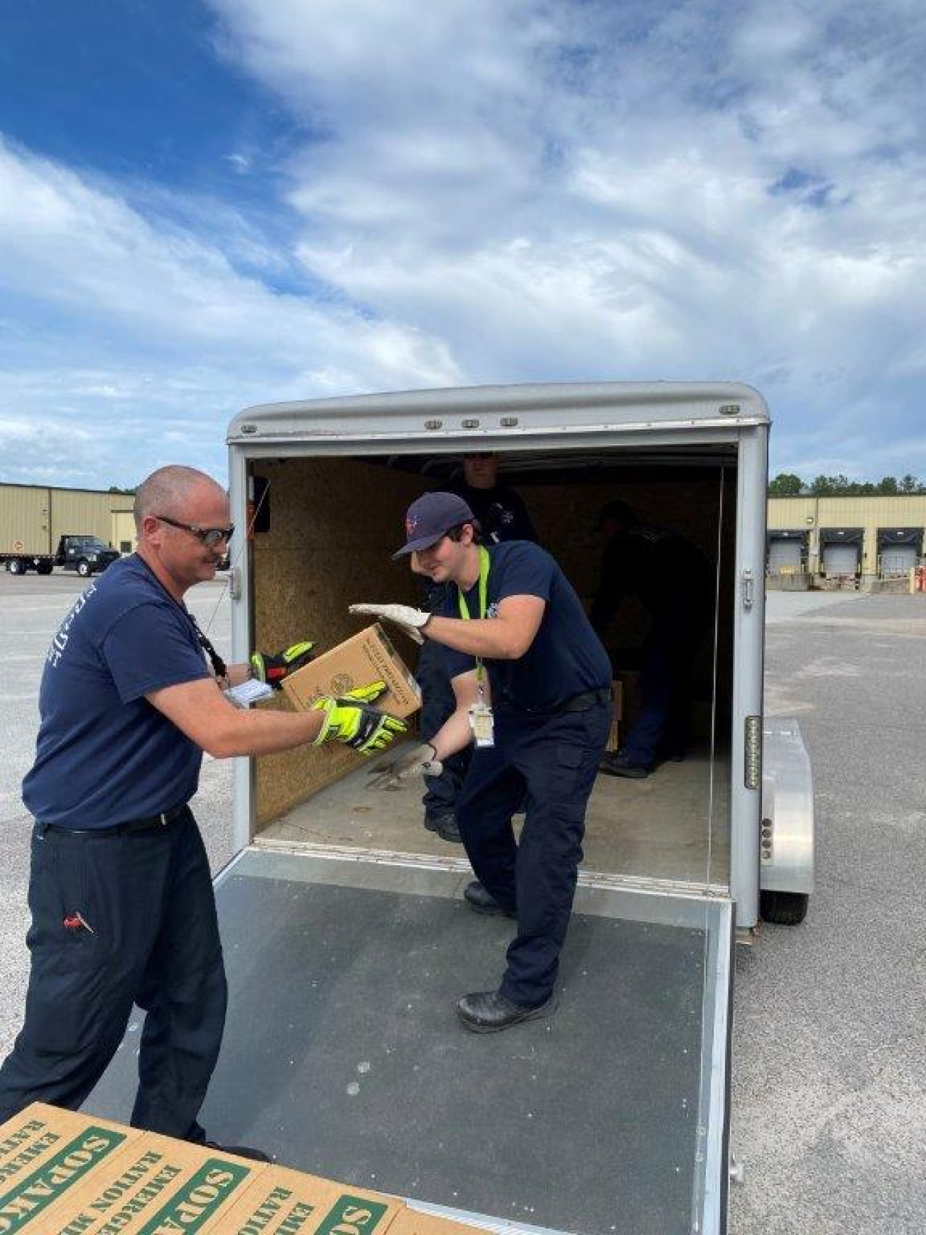Employees handing boxes to each other to load a truck with cardboard boxes