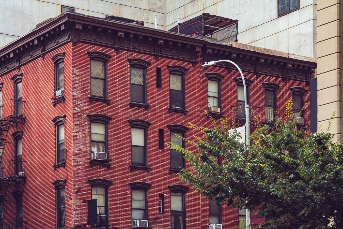 A multistory brick apartment building with a tree and streetlight.