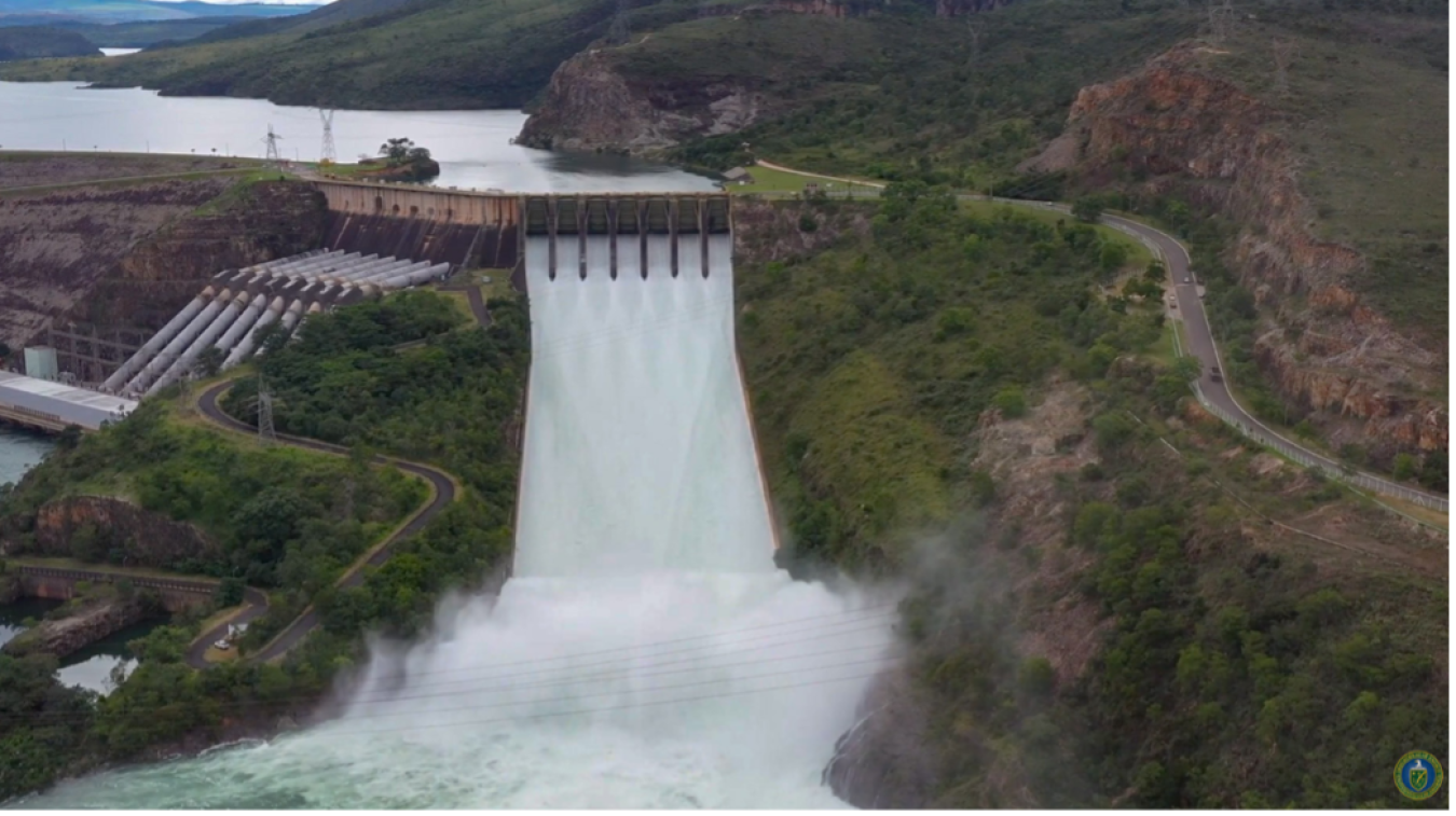 A dam releasing water, turning potential energy into generated energy through turbines