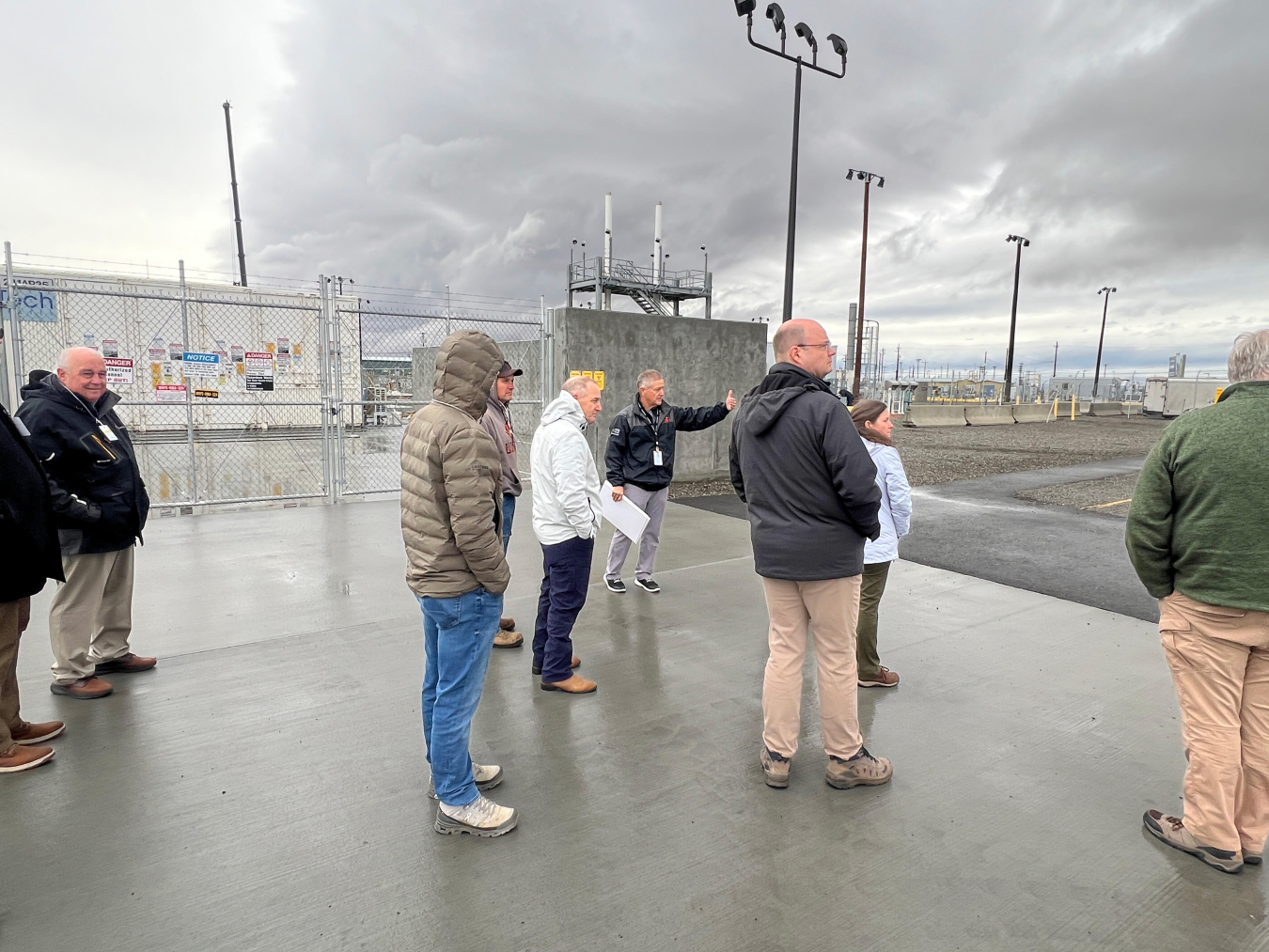 A group of people stand outside and take a tour of a facility