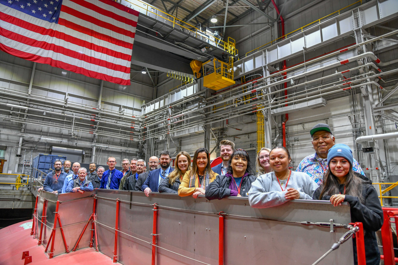 A large group of people pose for a photo while touring a laboratory
