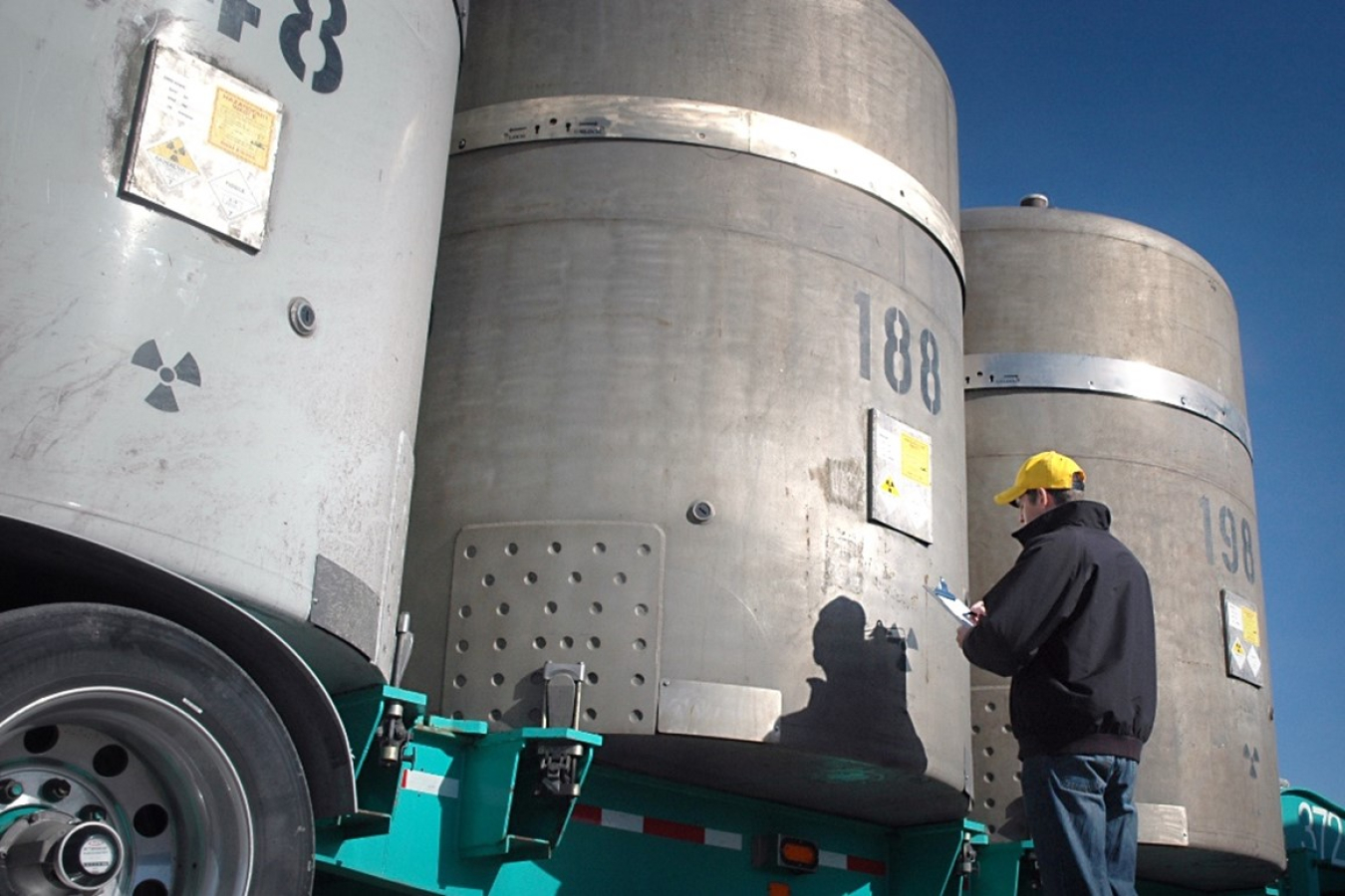 Three tanks on the back of a truck with a man holding a clip board and standing in front of it