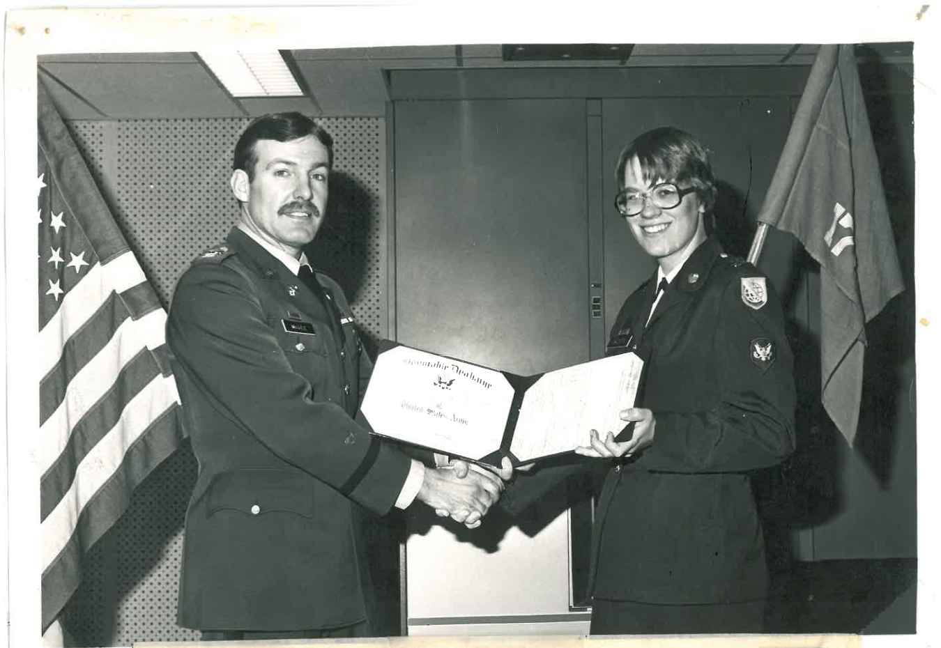 Two people in military uniforms. One receiving an award. 