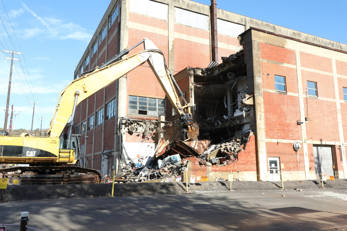 A large brick building being demolished by a crane