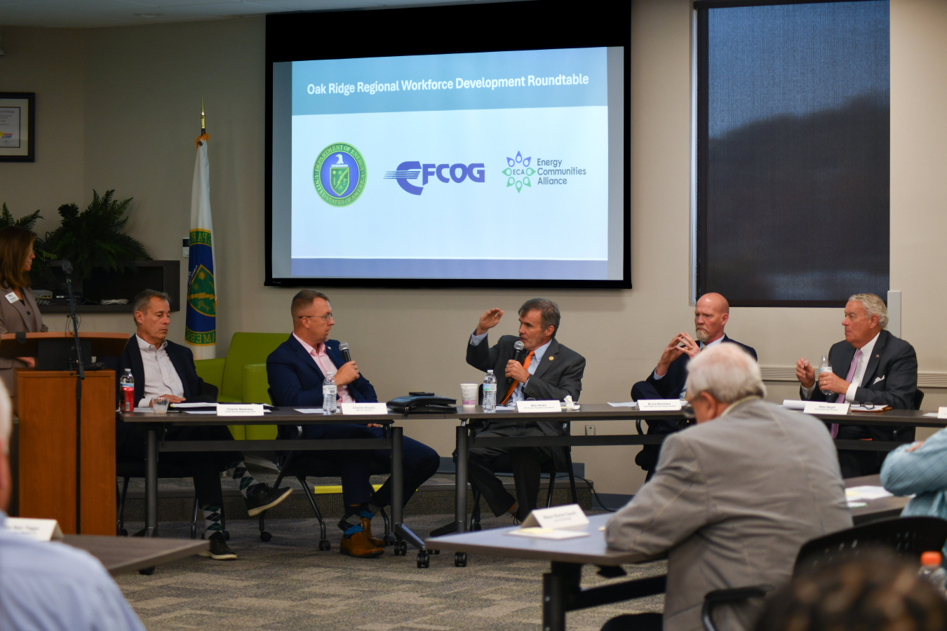 A panel of professionals sitting at the front of a room speaking to a crowd
