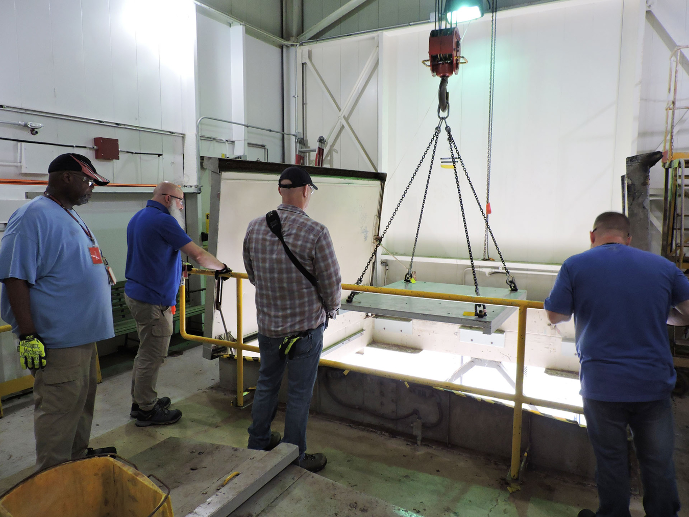 A group of employees uses a crane machine inside a laboratory building