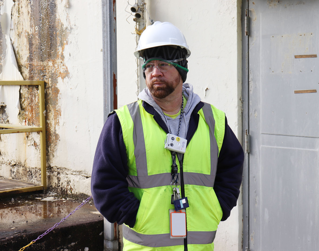 A man dressed in protective safety gear standing in front of a building