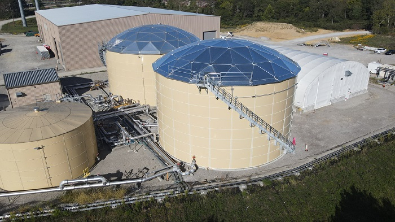 Aerial view of three large tan tanks, surrounded by facility buildings