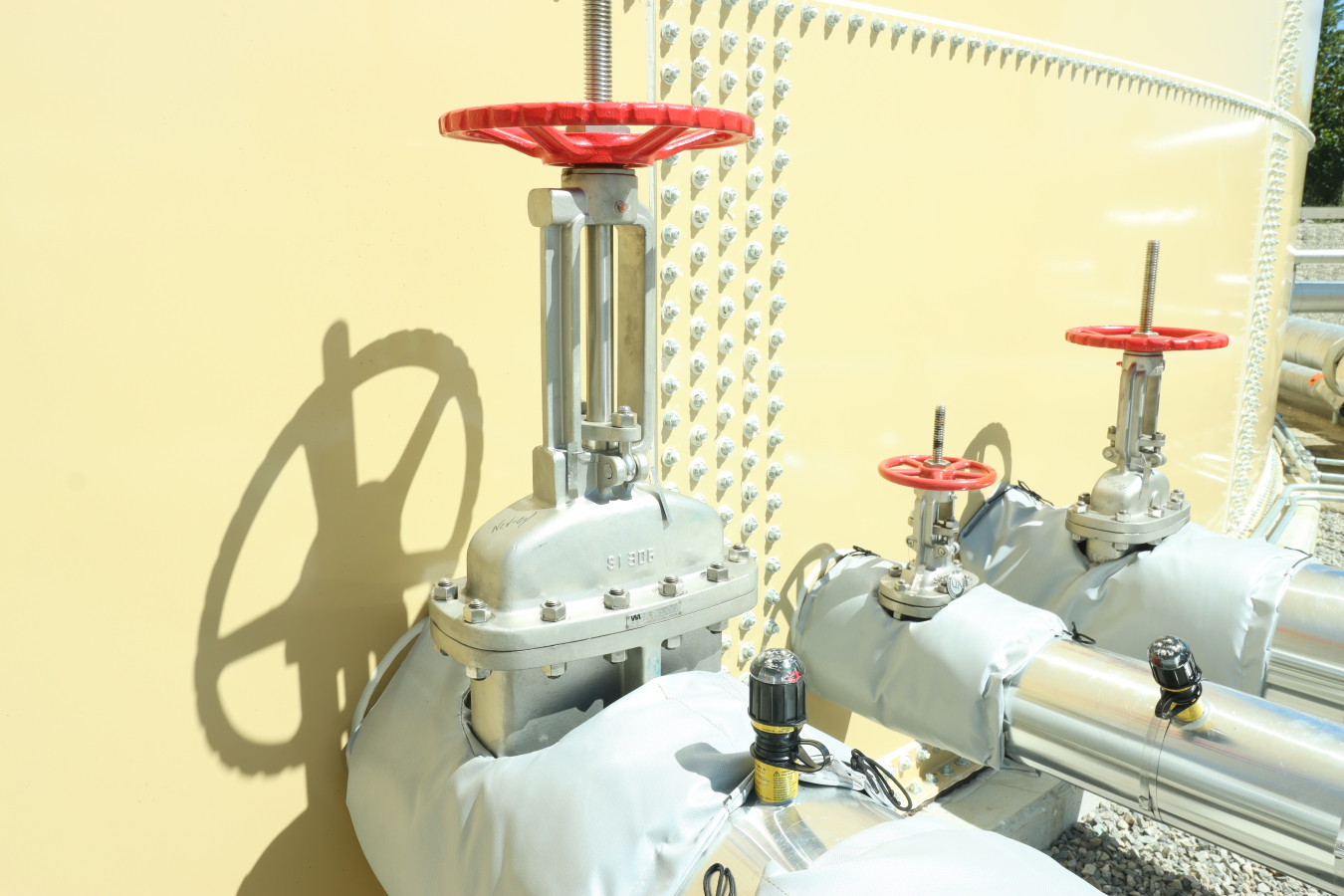 An upclose shot of three valves, with red handles, and the piping coming out of them 