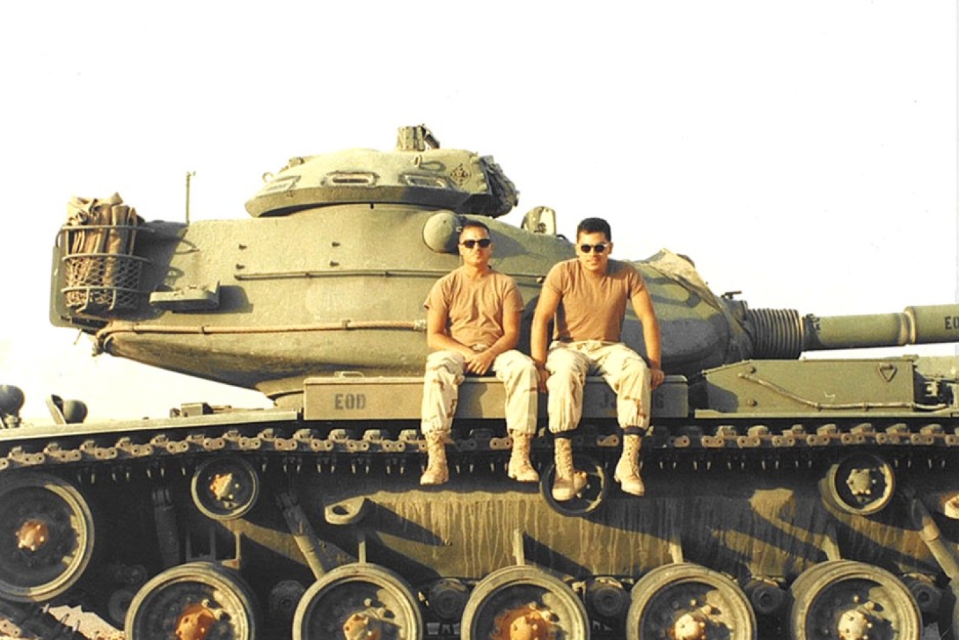A photo of two men in military clothes sitting on a tank