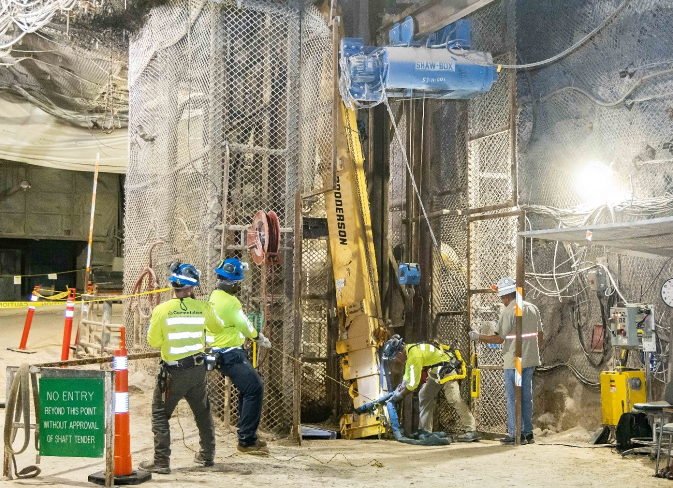 A group of employees wearing protective gear working on an underground drill 