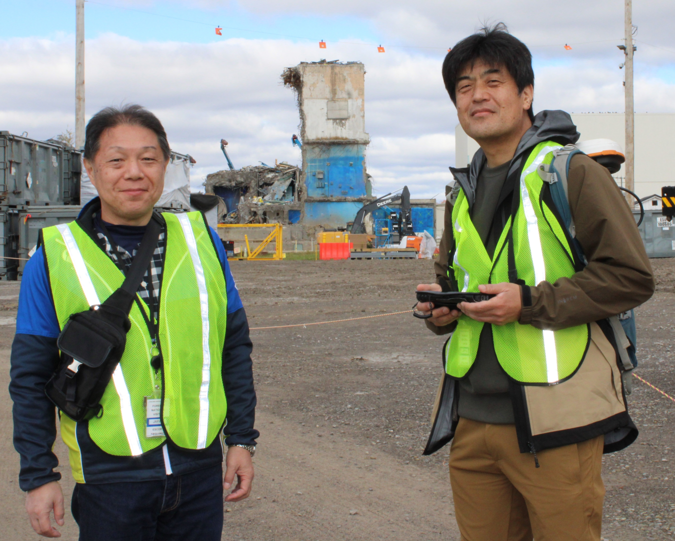 Two men in yellow safety vests smile for a picture