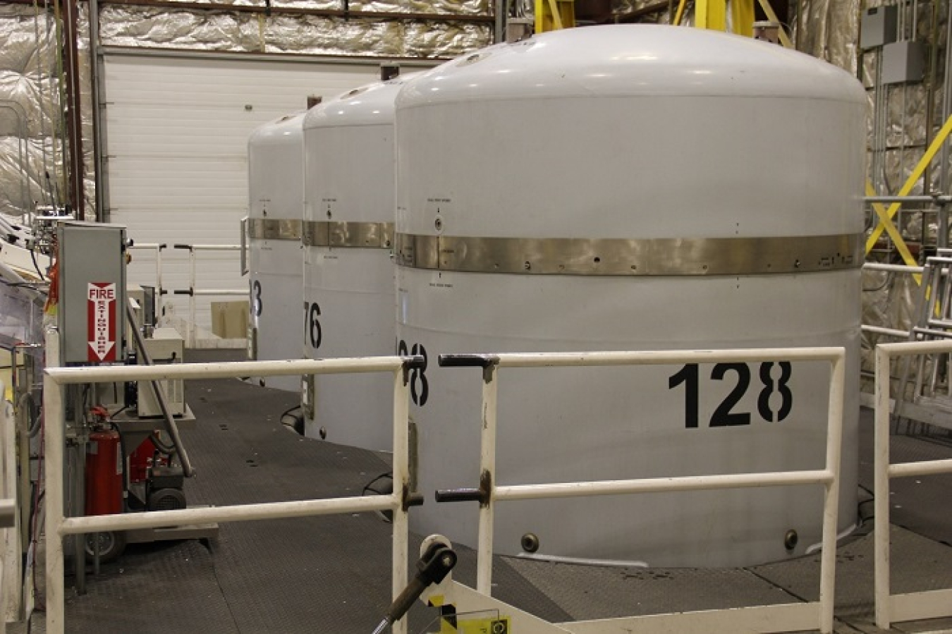 A row of large white storage tanks inside a facility building
