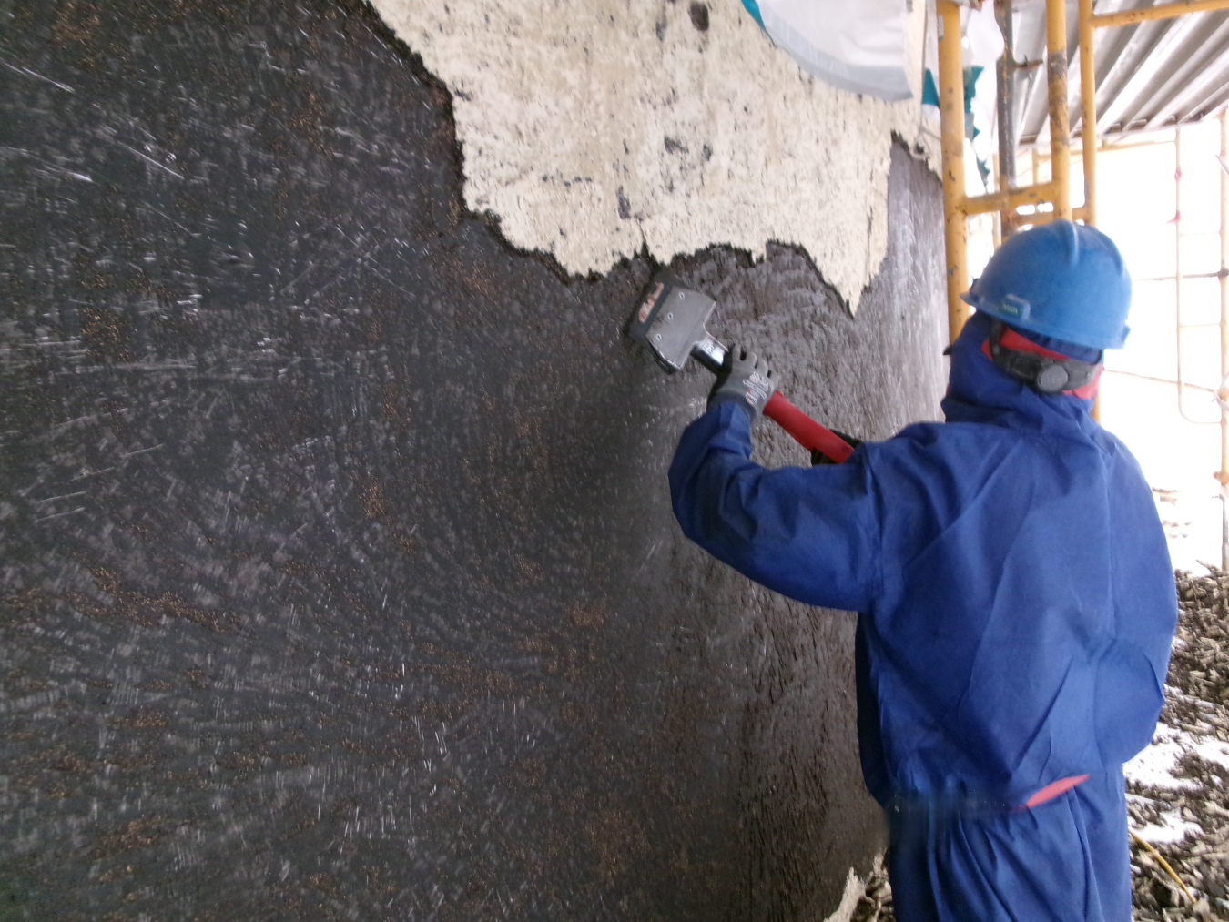 Hazmat worker scraping a wall