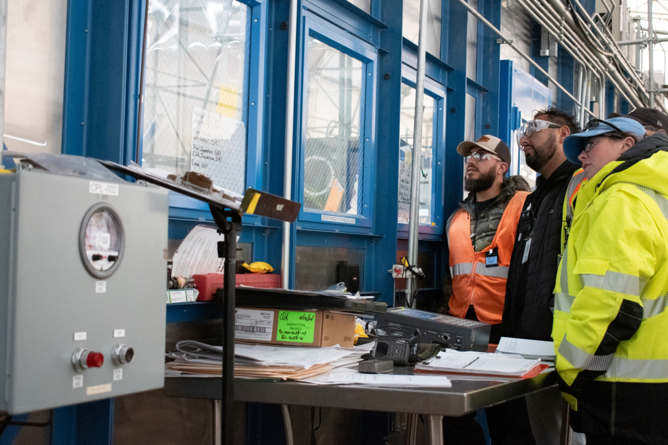 Workers stand outside windows and look inside a building