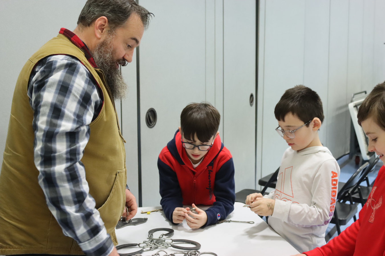 An adult and three kids stand around a table and work on science experiments 