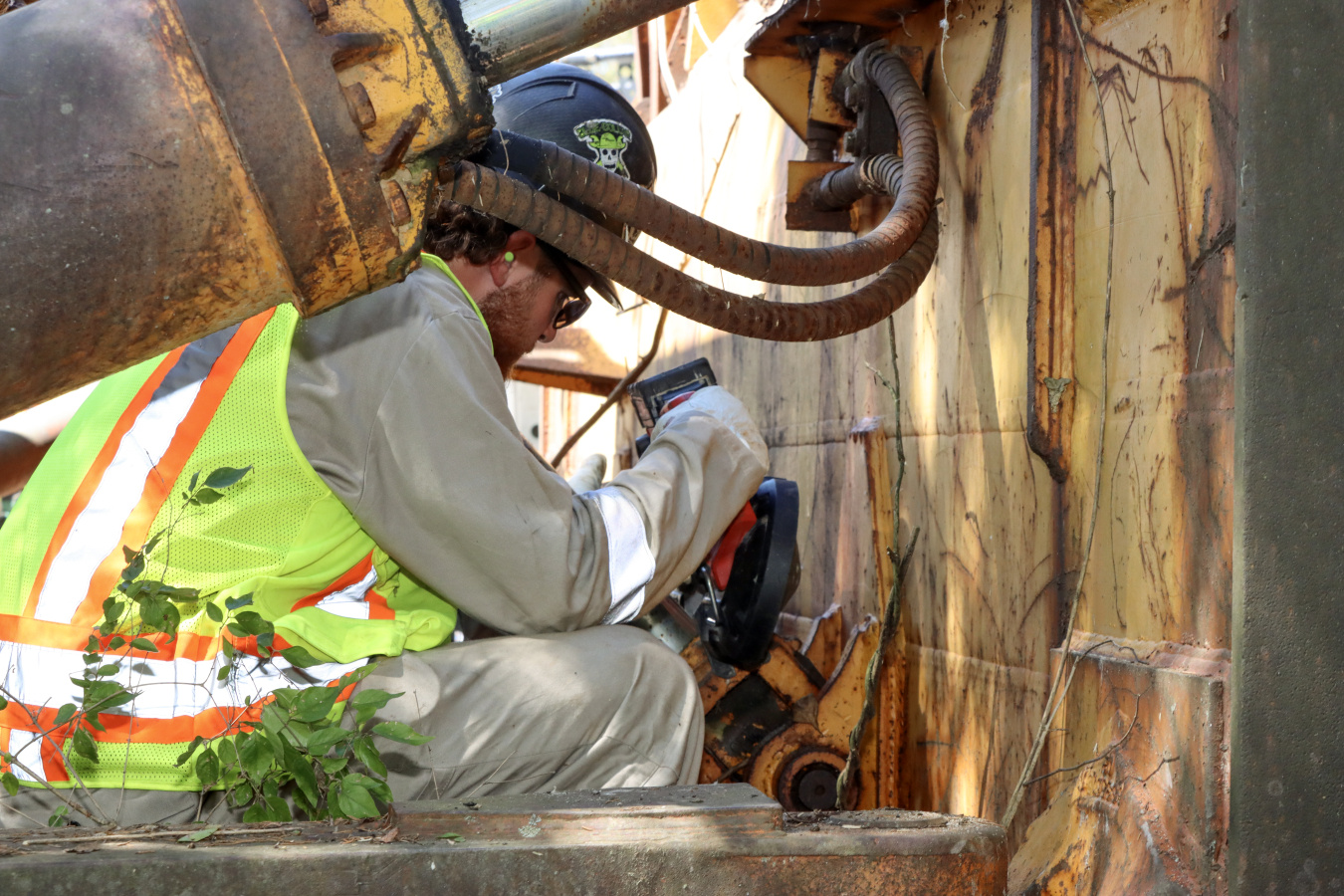 An employee in safety gear using an electric drill while removing a blade