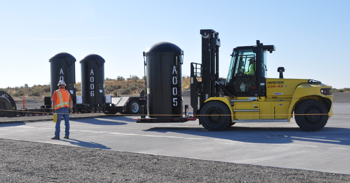 Work vehicles hauling and moving three black tank waste canisters
