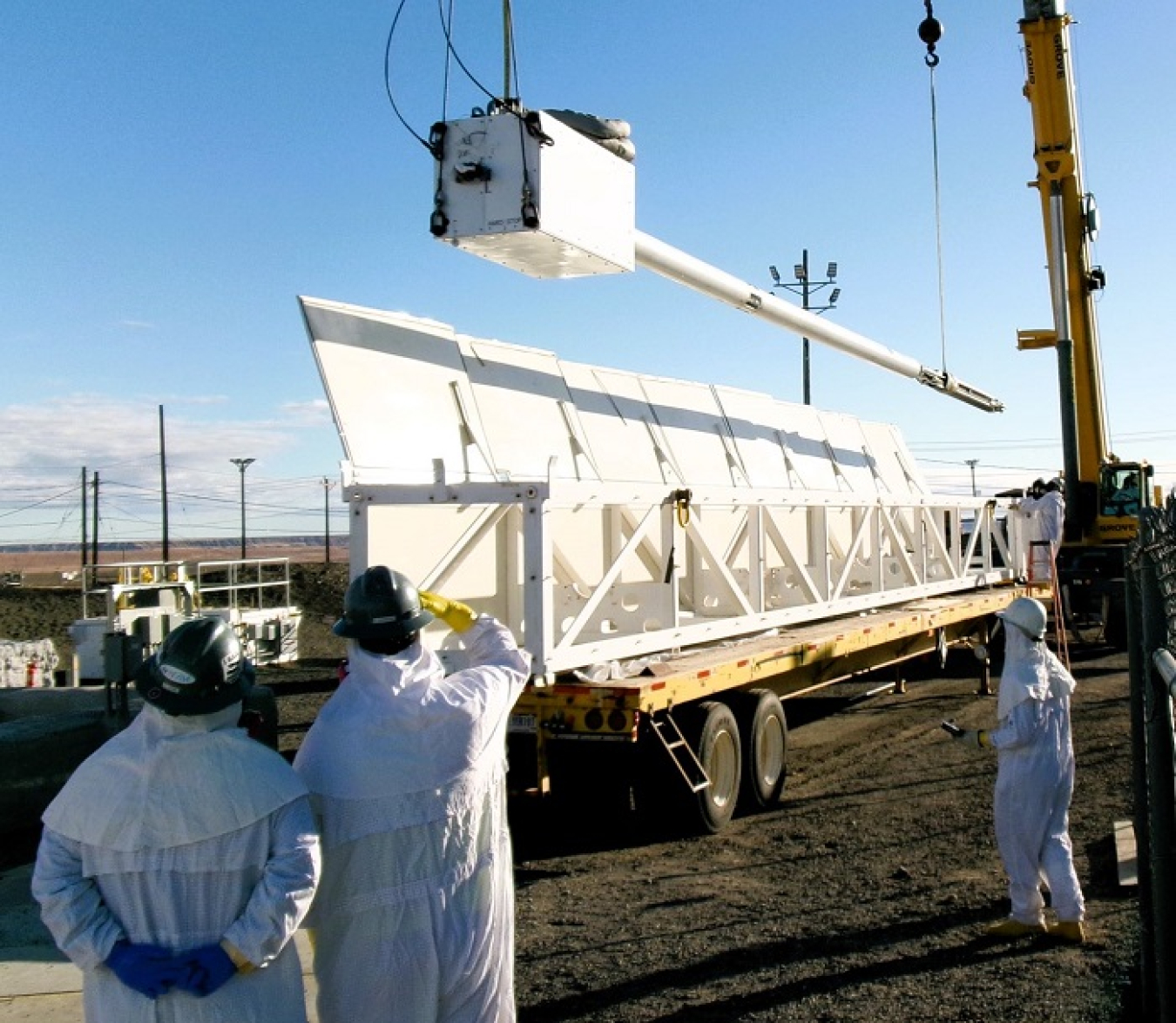 A group of employees outside watching a piece of equipment being installed