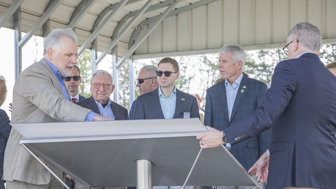 A group of individuals stand and look at an informational panel and talk to each other
