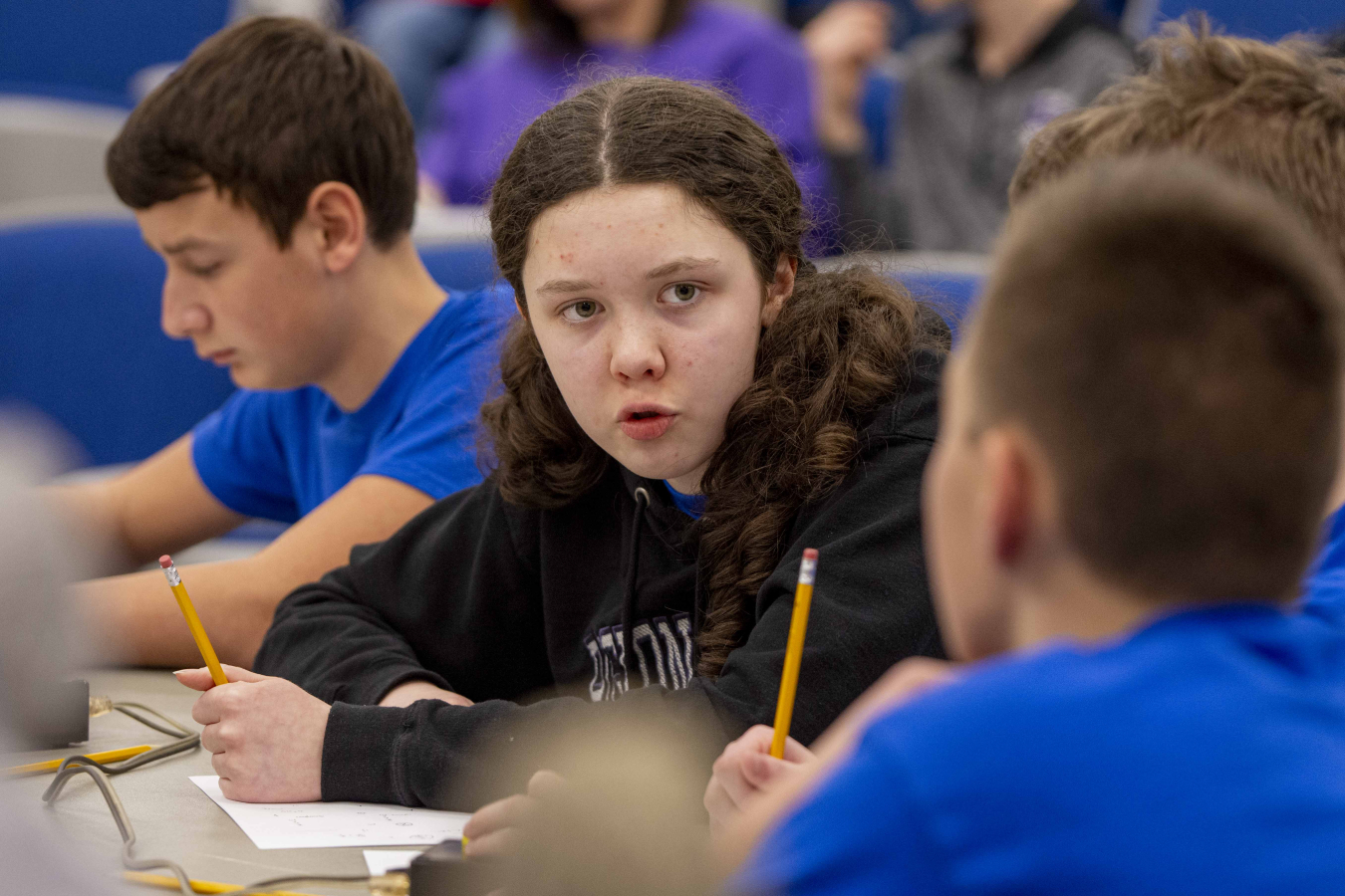 Middle school students sitting at a table participating in a science bowl