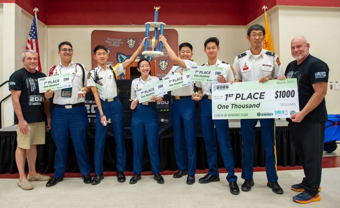 A group of students in Military uniforms pose for a picture after winning a science bowl competition