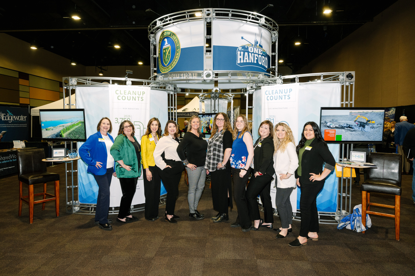 A group of people posing for a photo infront of an informational booth. 