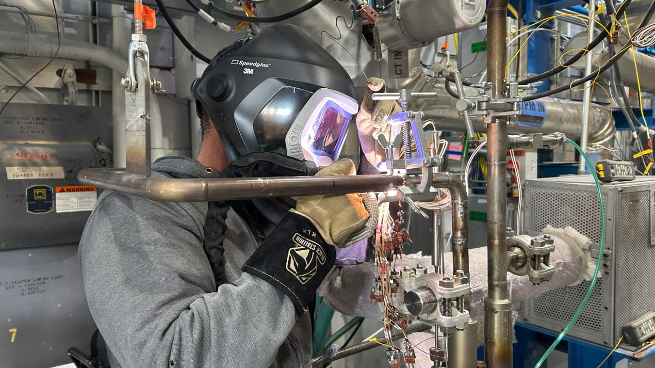Argonne workers weld an inlet pipe into the new cold trap device at the METL facility.