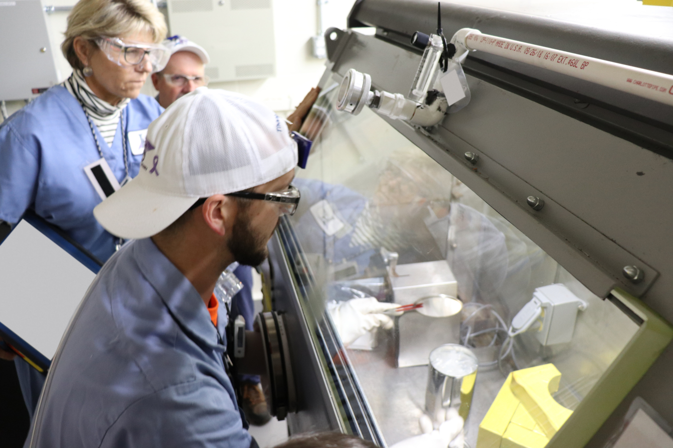 Three employees in a laboratory working in a glovebox