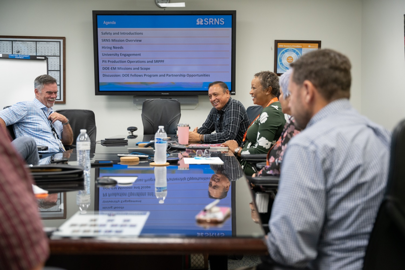 A group of fellows and employees sit at a conference table and talk to each other