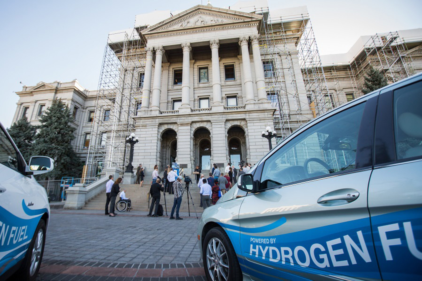 Two cars fueled by hydrogen in front of a state capitol building.