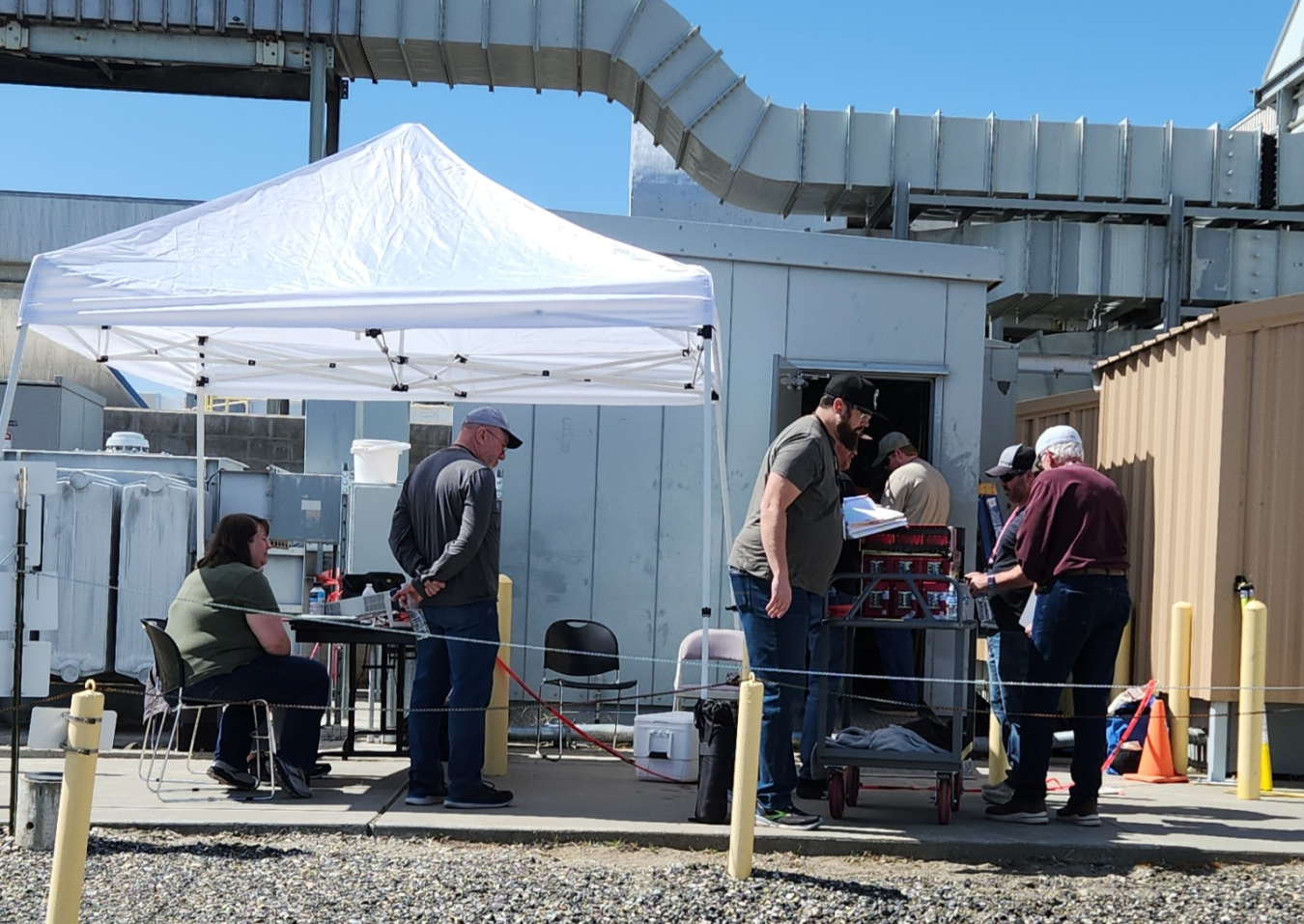 A tent outside with employees standing around an open door while testing sensors