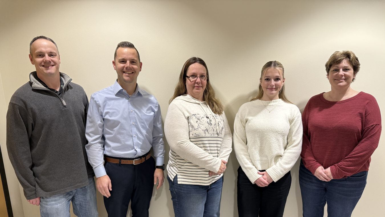 A group of five employees smile for a group photo