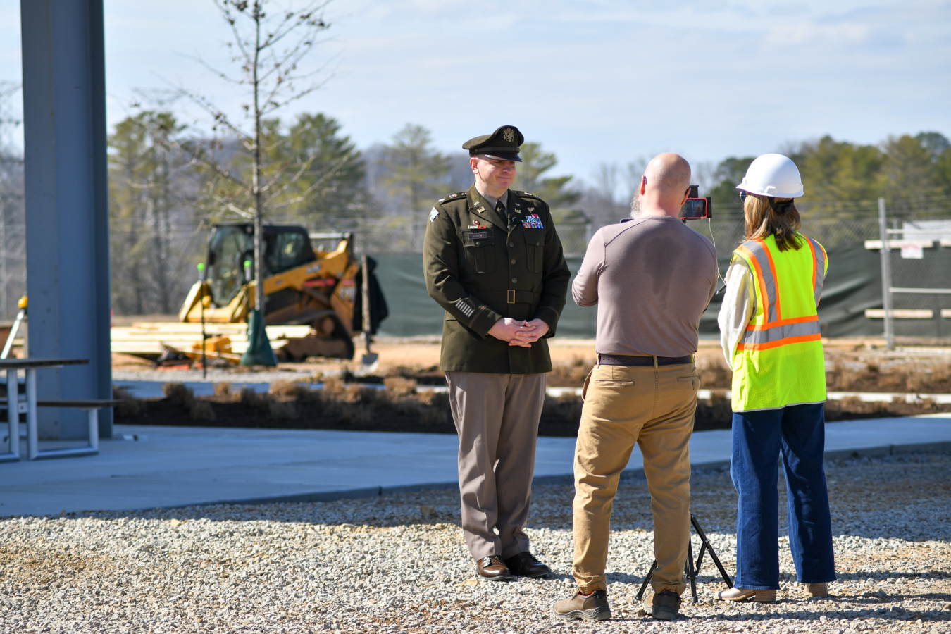 Two employees talk to a Lieutenant Colonel outside of a building 