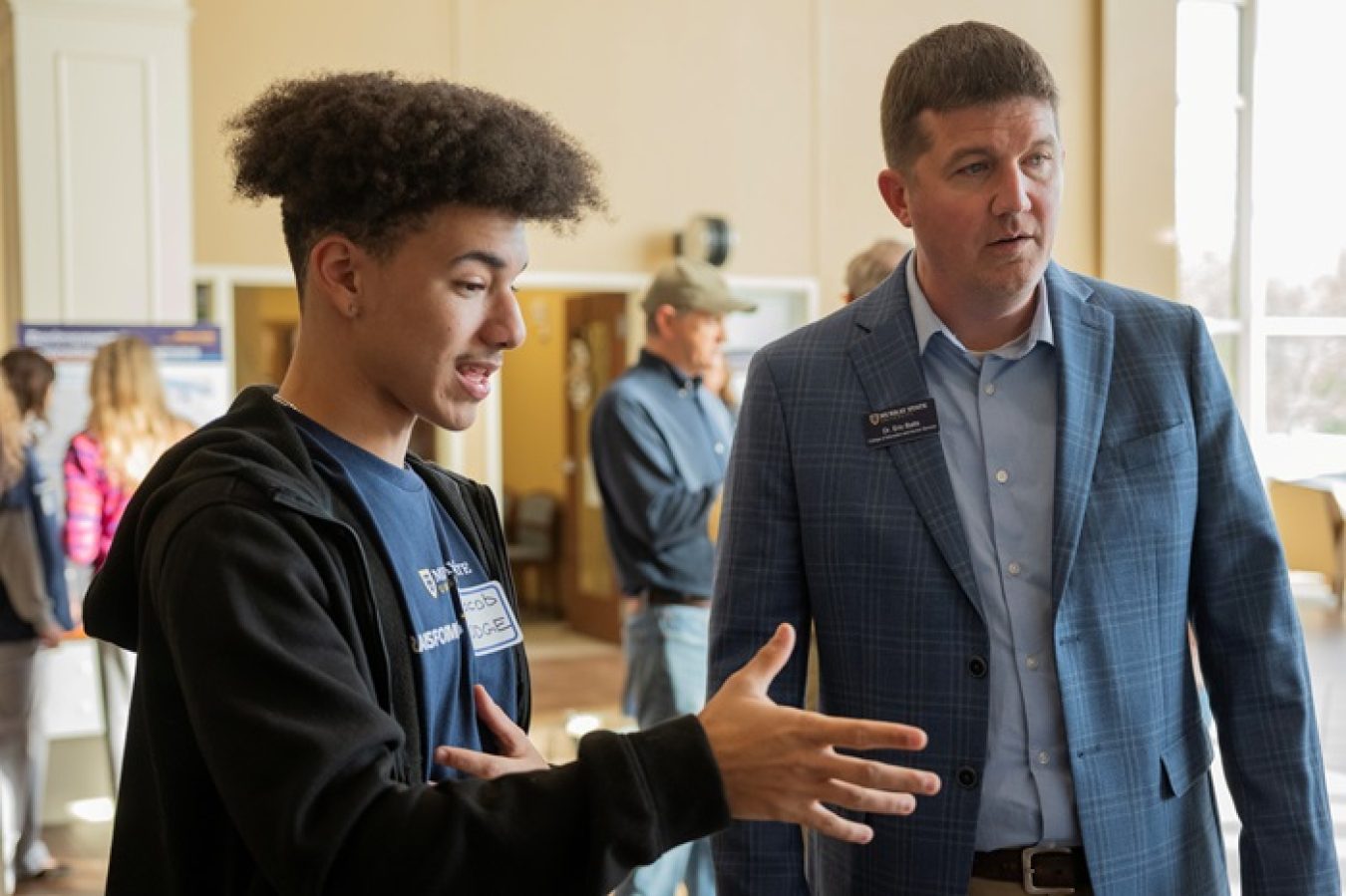Paducah Innovation Hub student Jacob Hodge, standing left, explains his research findings to Murray State University Assistant Professor Eric Batts. 