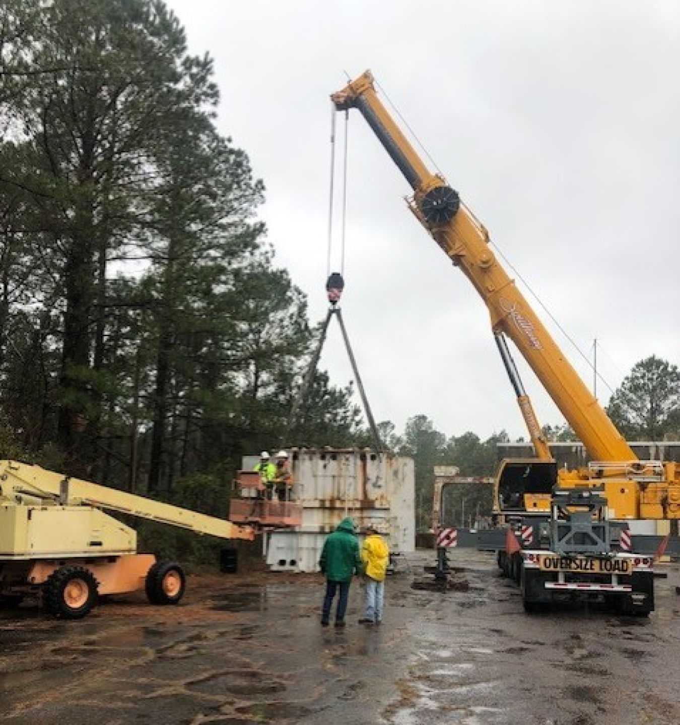 A yellow crane lifting a white transformer 