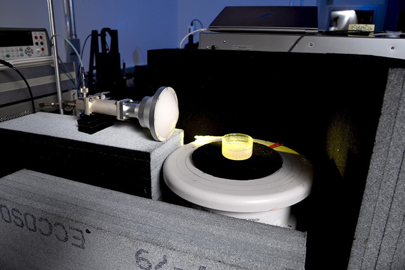 The Livermore team's 3D printing apparatus, about as long as a rolling pin, but twice as big around, points at a small cylinder of hardened resin.