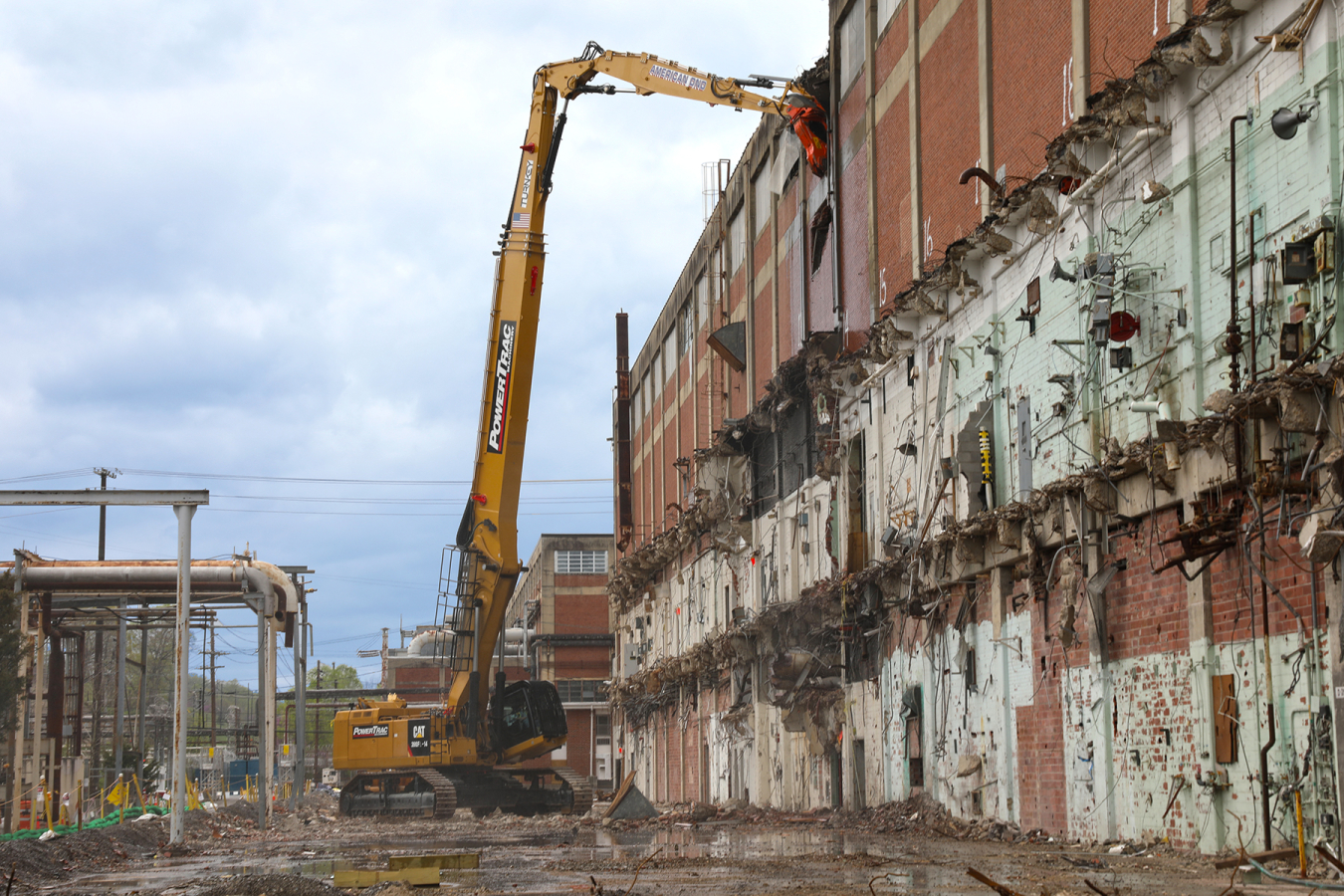 A yellow crane demolishing the side of a large building