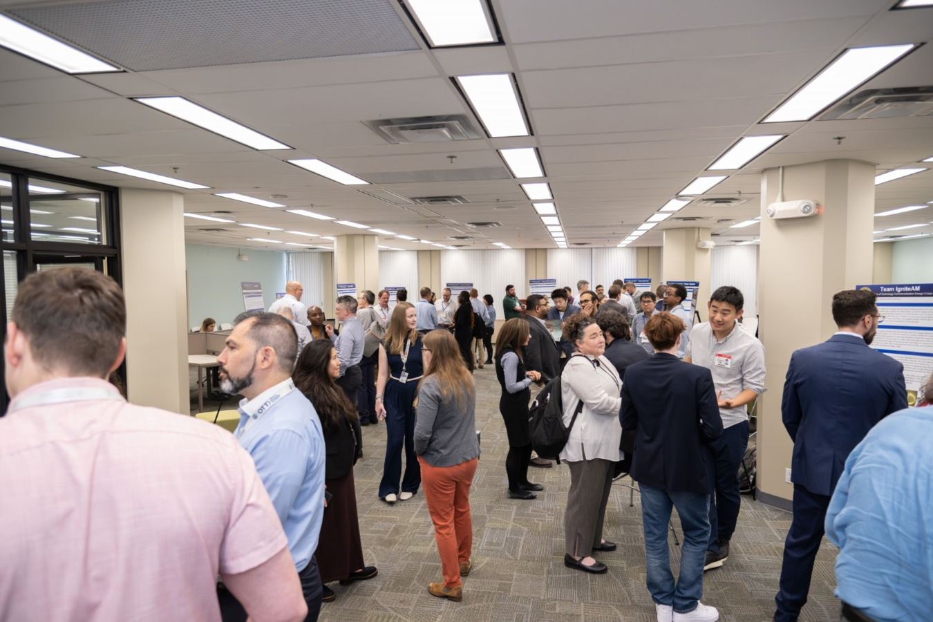 Groups of people viewing project summary posters in a room. 