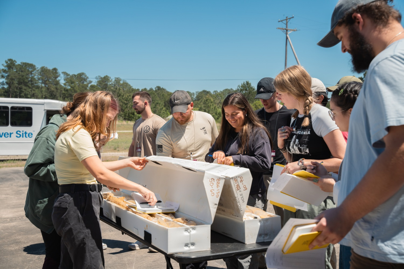 A group of people outside standing around a table while examining saltstone samples