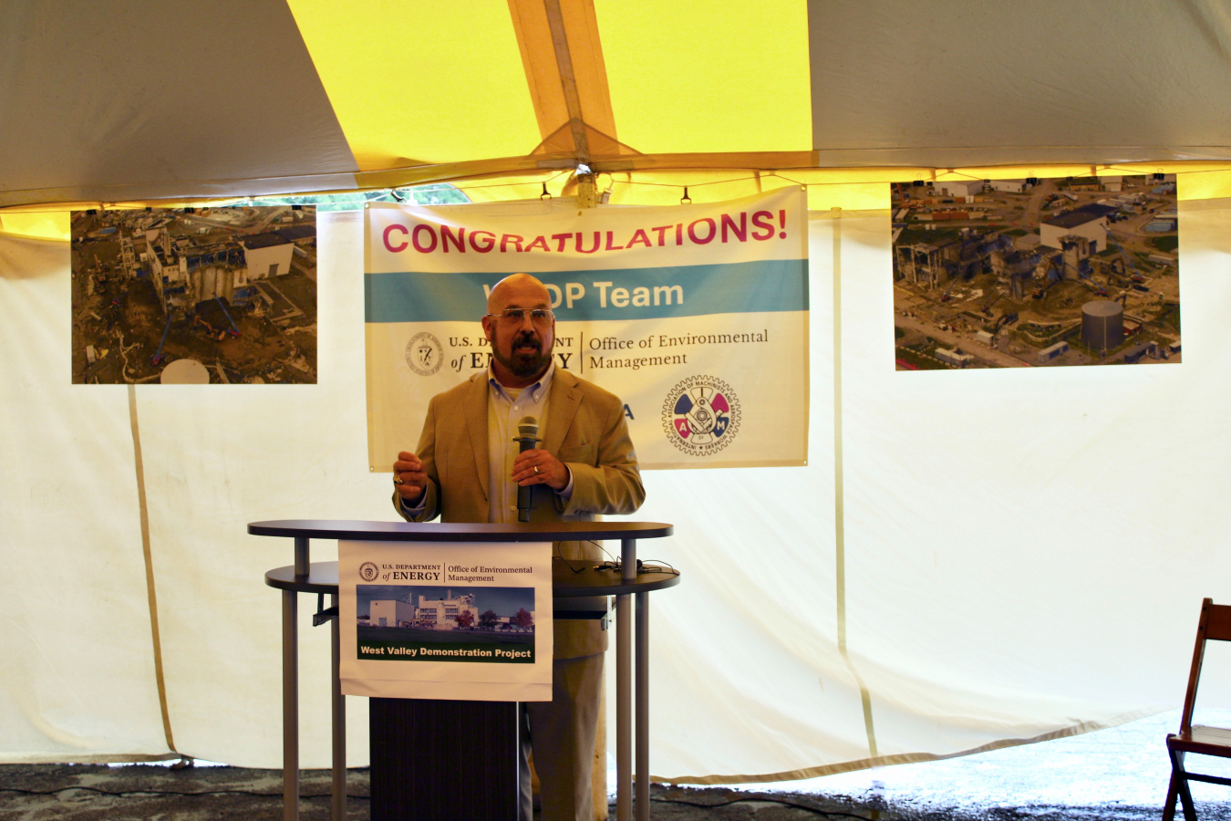 A DOE-EM Leader (male) on a stage standing behind a podium